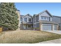 Charming two-story home with a three-car garage and brick and blue siding and large tree at 6493 W 98Th Ct, Westminster, CO 80021