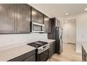 Kitchen with stainless steel appliances, gas range, quartz countertops and dark wood cabinets at 627 Nightsky St, Erie, CO 80516