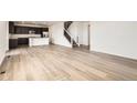 Spacious living area with wood floors, seamlessly connected to the kitchen and staircase at 627 Nightsky St, Erie, CO 80516