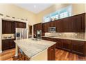 Spacious kitchen with granite countertops, island, stainless steel appliances, and dark wood cabinetry at 2730 Hanover N St, Denver, CO 80238