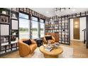 Stylish living room features book-lined walls, leather chairs, and large windows offering outdoor views at 10880 E Hinsdale Cir, Centennial, CO 80112