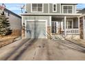 View of a home's front exterior, featuring a gray two-car garage, stone accents and front porch at 13694 Cherry St, Thornton, CO 80602