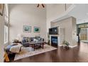 Cozy living room with high ceilings, fireplace, hardwood floors, and natural light from a large window at 10087 E Hawaii Pl, Aurora, CO 80247
