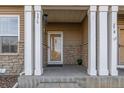 Charming front porch with stone accents, white columns, and a glass door at 9758 Laredo St # 37C, Commerce City, CO 80022