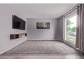 Spacious living room featuring plush carpeting, a large window, and a modern entertainment center at 2212 S Naples Way, Aurora, CO 80013