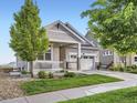 Single-story home with a covered porch, attached garage, landscaped yard, and charming curb appeal at 18280 W 85Th Dr, Arvada, CO 80007