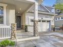 Inviting front porch with stone pillars, a wreath on the front door, and a two-car garage at 18280 W 85Th Dr, Arvada, CO 80007