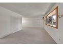 Spacious living room with large window, chandelier, and neutral carpeting at 13769 Omega Cir, Lone Tree, CO 80124