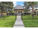 Attractive home featuring a fenced front yard and welcoming covered porch and an upper level balcony at 1690 Spruce St, Denver, CO 80220