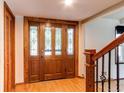Elegant foyer featuring a decorative wood door with sidelights and wood flooring, leading to the staircase at 11682 E Iowa Ave, Aurora, CO 80012