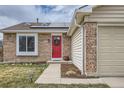Charming single-story home featuring a brick facade, attached two-car garage, a red door, and solar panels at 5587 S Simms Way, Littleton, CO 80127