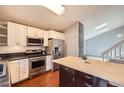 Modern kitchen with stainless steel appliances, white cabinets and a wooden island at 5587 S Simms Way, Littleton, CO 80127