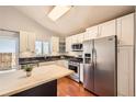 Updated kitchen featuring stainless steel appliances, black countertops, and light wood island at 5587 S Simms Way, Littleton, CO 80127