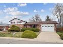 Traditional brick home featuring manicured bushes, green lawn, and attached garage on a sunny day at 10830 Claire Ln, Northglenn, CO 80234