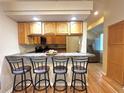 Open kitchen with bar seating, hardwood floors, wooden cabinets, and stainless steel refrigerator at 4493 Dunkirk Way, Denver, CO 80249