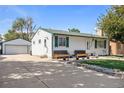 Home exterior featuring driveway leading to detached garage, well-kept lawn and front porch at 7891 Poplar St, Commerce City, CO 80022