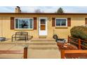 Cozy home entrance featuring a quaint bench, neat landscaping, and inviting white door at 1157 S Vivian St, Lakewood, CO 80228