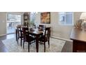 Cozy dining room with hardwood floors, a wooden table set for six, and a view to the outside deck at 6905 Fraser Cir, Frederick, CO 80530