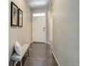 Neutral-toned entryway with hardwood floors, a bench, and ample natural light filtering through the front door at 6905 Fraser Cir, Frederick, CO 80530