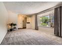Spacious living room with large window, plush carpet, and neutral tones perfect for relaxation at 10247 W Arkansas Ave, Lakewood, CO 80232