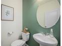 Half-bathroom with a decorative vanity, a round mirror, stylish wall paint, and modern fixtures at 7415 E 158Th Pl, Thornton, CO 80602