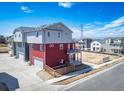 Rear view of a two-story home with a red and gray exterior and a garage entrance at 13616 E 103Rd Pl, Commerce City, CO 80022