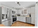 Modern kitchen with stainless steel appliances, white cabinets, and hardwood floors at 944 E Lily Ct, Highlands Ranch, CO 80126