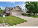 View of home with a two car garage and front lawn at 13441 Cherry St, Thornton, CO 80241