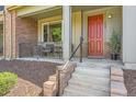Inviting front porch with stylish brick accents, leading to a vibrant red front door and manicured landscaping at 504 E Dry Creek Pl, Littleton, CO 80122