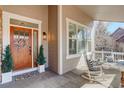 Inviting front porch with rocking chairs, potted plants, and a stylish front door with a wreath at 14032 Park Cove Dr, Broomfield, CO 80023