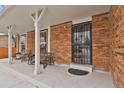 Inviting front porch featuring brick accents, comfortable seating, and stylish entrance door at 9135 Bellaire St, Thornton, CO 80229