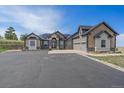 Charming exterior elevation with stone accents, three-car garage and long driveway at 575 Howling Cir, Elizabeth, CO 80107
