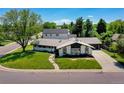 Well-maintained ranch-style home featuring a lush front lawn, mature trees, and an extended driveway leading to a two-car garage at 6220 E 5Th Ave, Denver, CO 80220