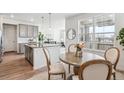 Bright dining area features a rustic wood table, stylish chairs, wood floors, and a large window showcasing the neighborhood at 718 176Th Ave, Broomfield, CO 80023