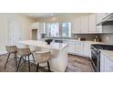 Bright kitchen features white cabinets, marble countertops, island seating, stainless appliances, and wood flooring at 682 Belay St, Erie, CO 80516