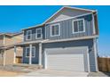 Charming blue two-story home with a white garage door and covered entryway at 2212 Crosswind St, Fort Lupton, CO 80621
