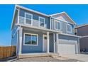 Front elevation showcasing the blue siding, white trim, covered porch, and attached garage at 2212 Crosswind St, Fort Lupton, CO 80621