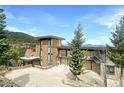 Contemporary home showcasing a stone facade, large windows, and a spacious driveway with scenic mountain backdrop at 180 Outpost Ln, Evergreen, CO 80439