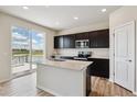 Well-lit kitchen with stainless appliances, dark cabinets, and island sink near sliding door access at 4285 Gozzer Ranch Dr, Elizabeth, CO 80107