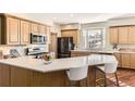 Well-lit kitchen with wooden cabinets, stainless steel appliances, white countertops, and breakfast bar at 9261 Millcreek Ct, Highlands Ranch, CO 80126