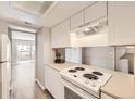 Clean kitchen with white appliances and view to the backyard through sliding glass doors at 12143 Melody Dr # 104, Denver, CO 80234