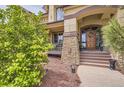 Inviting front entrance with decorative wood door, stone accents, and manicured landscaping at 6411 Sand Rose Ct, Castle Rock, CO 80108