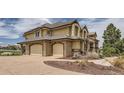 Elegant home featuring an attached three-car garage with stone accents and a wide driveway at 6411 Sand Rose Ct, Castle Rock, CO 80108