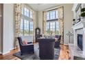 Bright living room featuring large windows, hardwood floors, fireplace, and stylish seating at 6411 Sand Rose Ct, Castle Rock, CO 80108