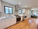Bright kitchen features stainless steel appliances, white cabinets, and beautiful hardwood floors at 2895 Poplar St, Denver, CO 80207