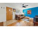 Inviting living room featuring hardwood floors, a ceiling fan, and a bright blue accent wall at 6755 W 33Rd Ave, Wheat Ridge, CO 80033