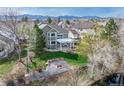 Aerial view of the home with a lush backyard, covered patio, and fire pit near the creek at 6802 Poppy Ct, Arvada, CO 80007