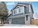 Side view of gray two-story home with a two-car garage and manicured landscape at 9208 W 100Th Pl, Broomfield, CO 80021