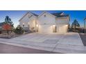 Two-story white farmhouse with a two-car garage and neatly landscaped yard at 3308 Carabiner St, Castle Rock, CO 80108