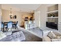 Open-concept living room features a TV, kitchen view, dining table, and modern decor at 8481 W Union Ave # 4-203, Littleton, CO 80123